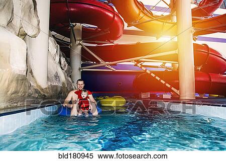 Stock Photography - Caucasian father and daughter swimming under water park slide. Fotosearch