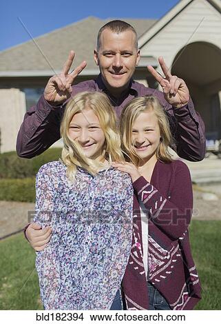 Picture - Caucasian father and daughters smiling in yard. Fotosearch