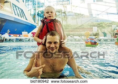Stock Image - Caucasian father and son swimming in pool. Fotosearch