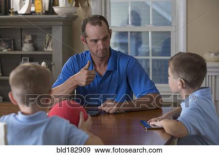 Caucasian father and sons signing at dinner table View Large Photo Image Stock Photo - Caucasian father and sons signing at dinner table. Fotosearch