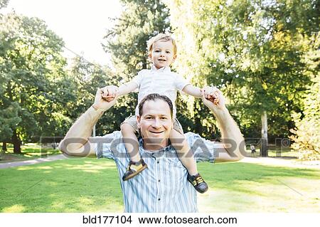 Picture - Caucasian father carrying son in park. Fotosearch