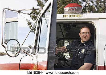 Picture - Caucasian firefighter smiling in fire truck. Fotosearch
