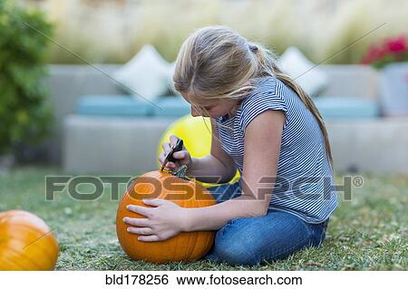 Stock Photograph - Caucasian girl carving pumpkin. Fotosearch