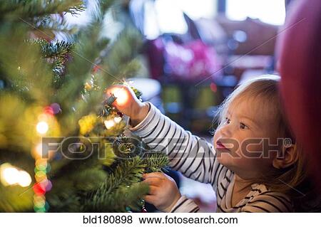 Stock Photo - Caucasian girl decorating Christmas tree. Fotosearch