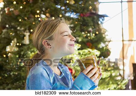 Stock Photo - Caucasian girl drinking hot cocoa at Christmas. Fotosearch