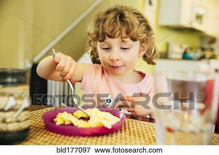 Stock Photo - Caucasian girl eating at table. Fotosearch
