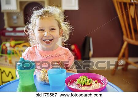 Stock Photo - Caucasian girl eating in high chair. Fotosearch