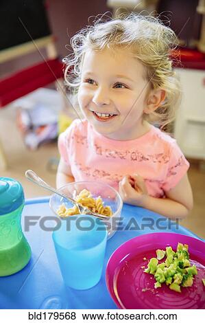 Stock Photo - Caucasian girl eating in high chair. Fotosearch