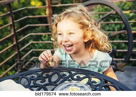 Picture - Caucasian girl eating on patio. Fotosearch