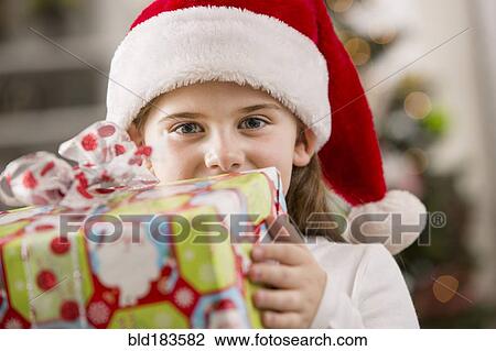 Stock Image - Caucasian girl holding Christmas gift. Fotosearch