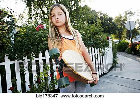 Caucasian girl holding skateboard on sidewalk View Large Photo Image Stock Photo - Caucasian girl holding skateboard on sidewalk. Fotosearch