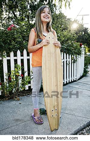 Caucasian girl holding skateboard on sidewalk View Large Photo Image Stock Photo - Caucasian girl holding skateboard on sidewalk. Fotosearch