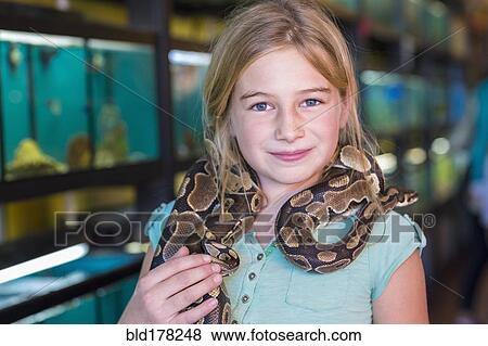 Stock Photo - Caucasian girl holding snake in pet store. Fotosearch