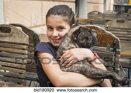Stock Image - Caucasian girl hugging dog at cafe. Fotosearch