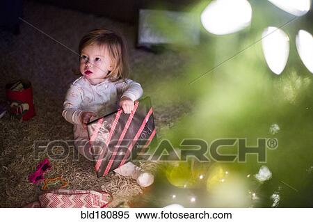 Stock Photography - Caucasian girl opening Christmas gift. Fotosearch