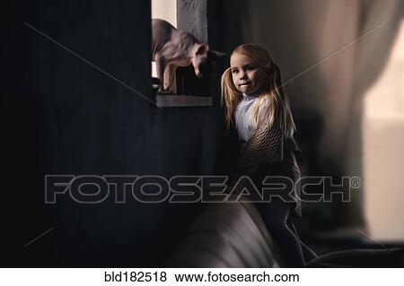 Stock Photo - Caucasian girl petting cat in window. Fotosearch