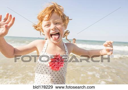 Stock Photo - Caucasian girl playing in waves on beach. Fotosearch