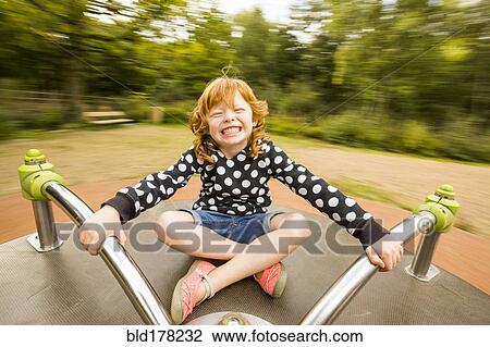 Stock Image - Caucasian girl playing on merry-go-round. Fotosearch