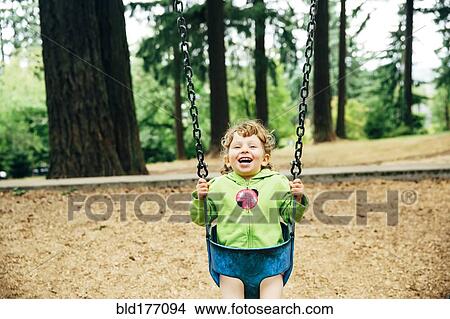Picture - Caucasian girl playing on swing. Fotosearch