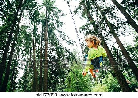 Stock Image - Caucasian girl playing on swing. Fotosearch