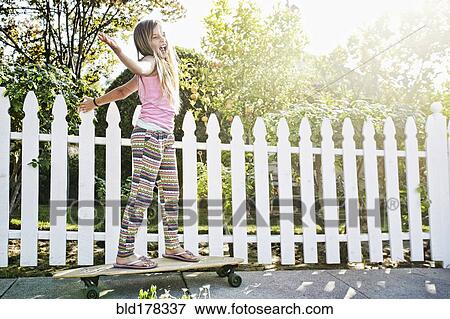 Stock Photo - Caucasian girl riding skateboard on sidewalk. Fotosearch