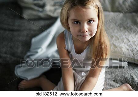 Stock Image - Caucasian girl smiling on bed. Fotosearch