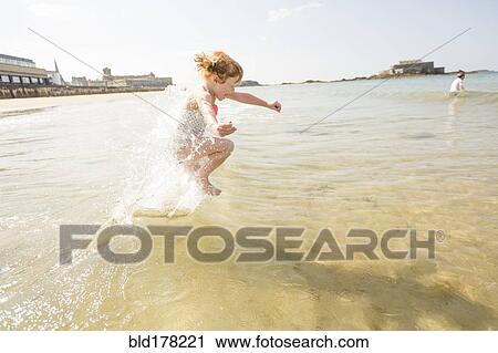 Caucasian girl splashing in waves on beach View Large Photo Image Stock Image - Caucasian girl splashing in waves on beach. Fotosearch