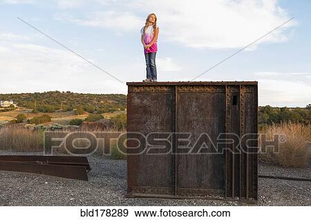 Stock Photo - Caucasian girl standing on rusting structure outdoors. Fotosearch