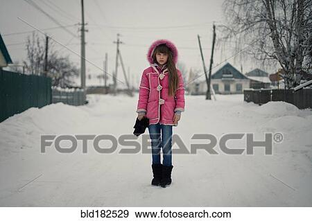 Stock Photo - Caucasian girl standing on snowy street. Fotosearch