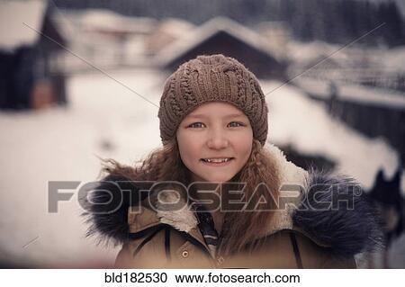 Stock Image - Caucasian girl wearing beanie hat and coat in snow. Fotosearch