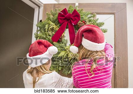 Stock Photography - Caucasian girls hanging Christmas wreath. Fotosearch