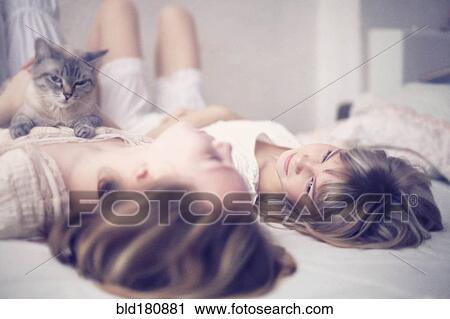 Stock Image - Caucasian girls laying on bed. Fotosearch