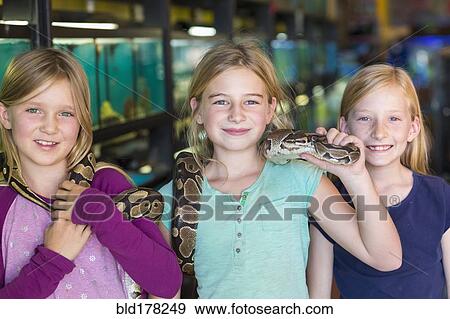 Stock Photo - Caucasian girls playing with snake in pet store. Fotosearch