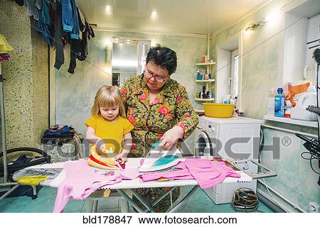 Stock Photo - Caucasian grandmother and granddaughter ironing laundry. Fotosearch