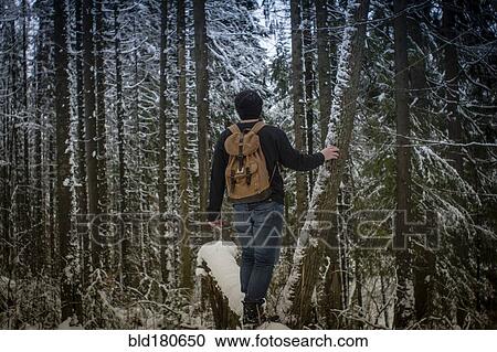 Stock Image - Caucasian hiker standing in snowy forest. Fotosearch