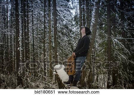 Stock Image - Caucasian hiker standing in snowy forest. Fotosearch
