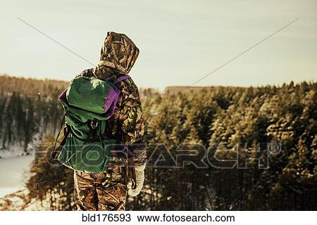 Stock Image - Caucasian hiker standing on hilltop. Fotosearch