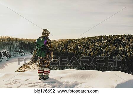 Stock Image - Caucasian hiker standing on snowy hilltop. Fotosearch