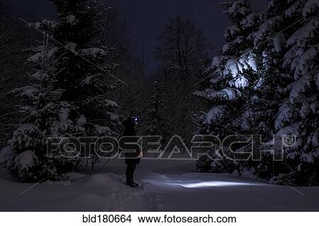 Picture - Caucasian hiker wearing headlamp in snowy forest. Fotosearch