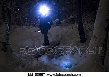 Stock Photo - Caucasian hiker wearing headlamp balancing on forest log. Fotosearch