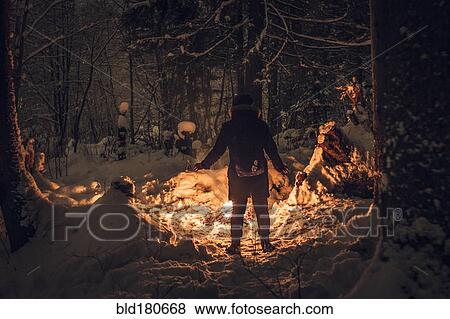Stock Photo - Caucasian hiker wearing headlamp exploring forest. Fotosearch