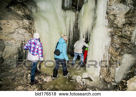 Stock Photo - Caucasian hikers exploring stalactite cave. Fotosearch