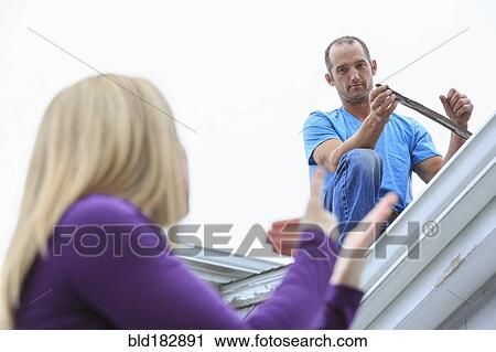 Stock Image - Caucasian homeowner signing to deaf roofer. Fotosearch