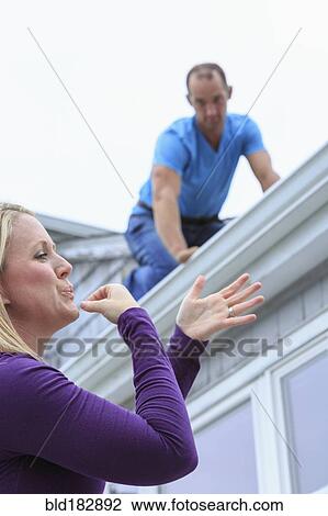 Stock Image - Caucasian homeowner signing to deaf roofer. Fotosearch
