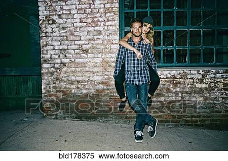 Stock Photography - Caucasian man carrying girlfriend piggyback outdoors. Fotosearch