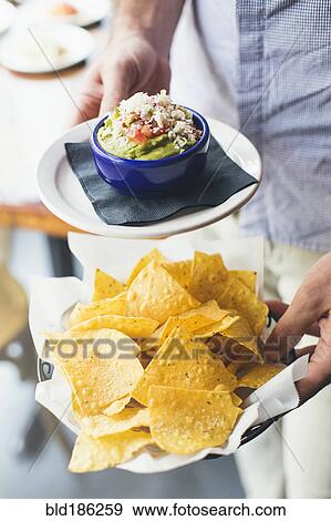 Stock Photo - Caucasian man carrying guacamole and tortilla chips. Fotosearch