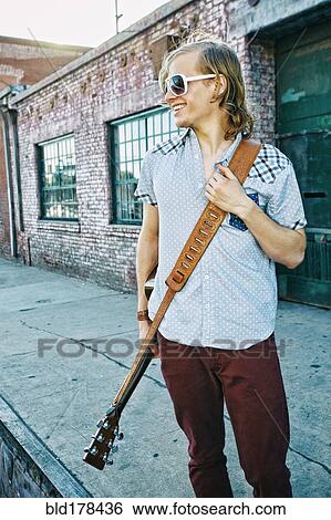 Caucasian man carrying guitar outdoors View Large Photo Image Stock Photograph - Caucasian man carrying guitar outdoors. Fotosearch