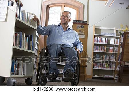 Stock Image - Caucasian man choosing book in library. Fotosearch