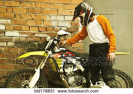 Stock Image - Caucasian man examining dirt bike. Fotosearch