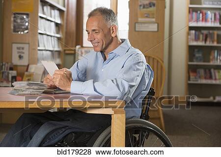 Stock Photo - Caucasian man examining dvds in library. Fotosearch